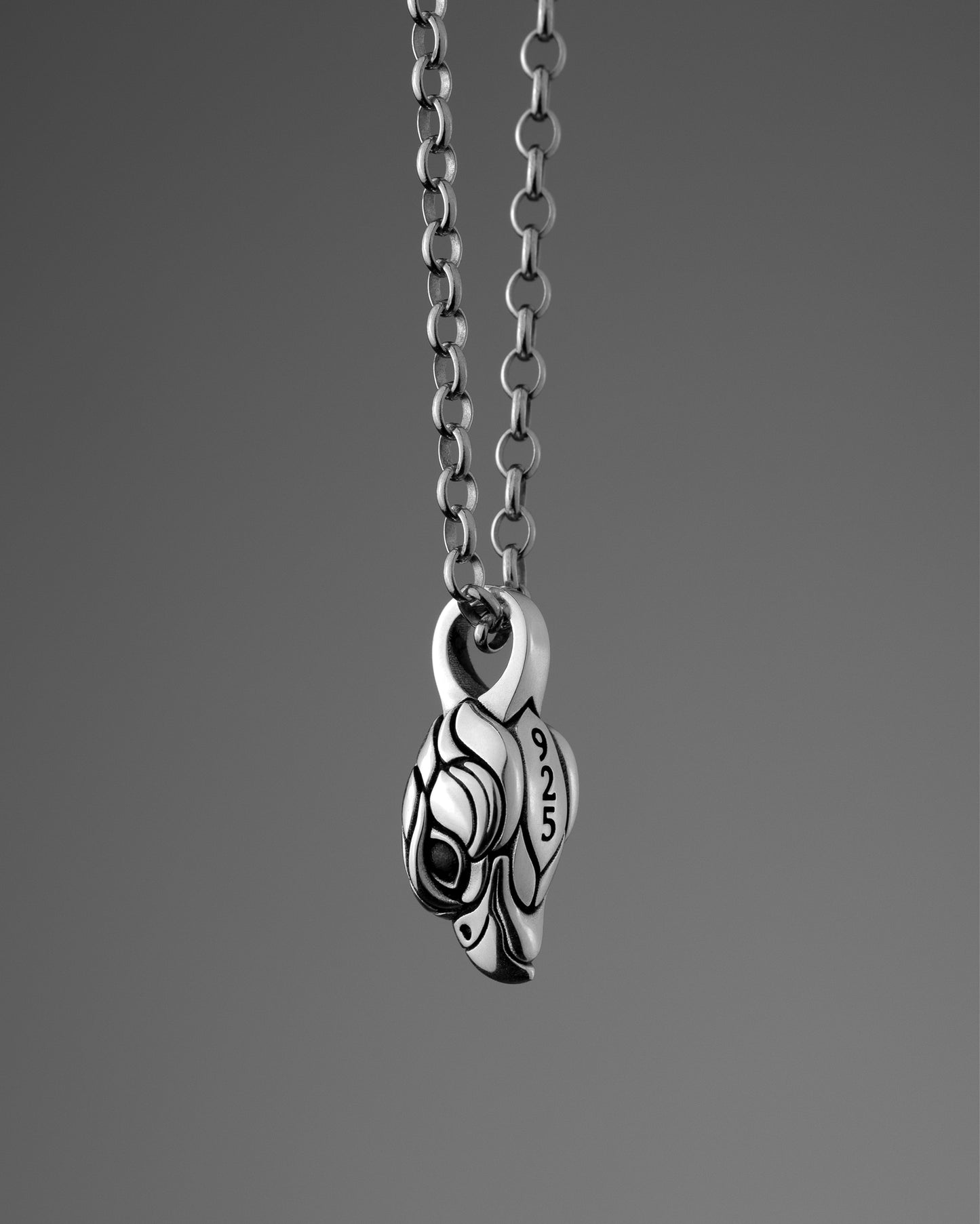 Sterling silver necklace with a small falcon pendant on a gray background