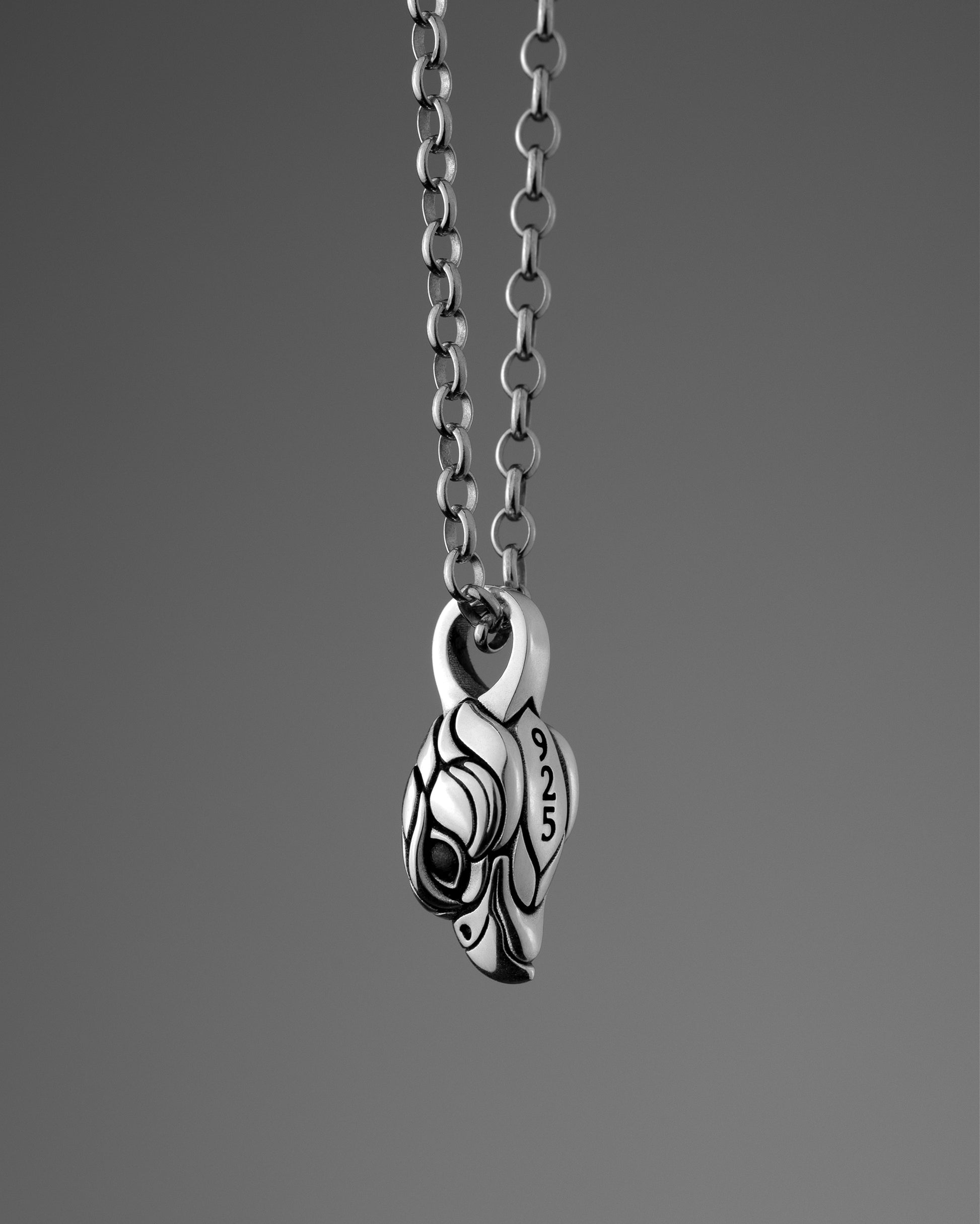 Sterling silver necklace with a small falcon pendant on a gray background